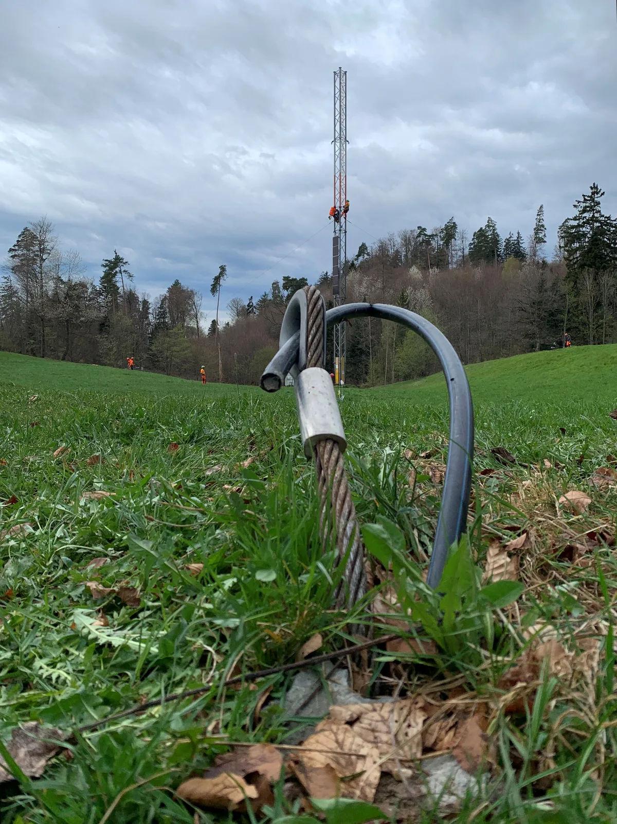 Man sieht eine Verankerung für Abspannseile auf einer Wiese.