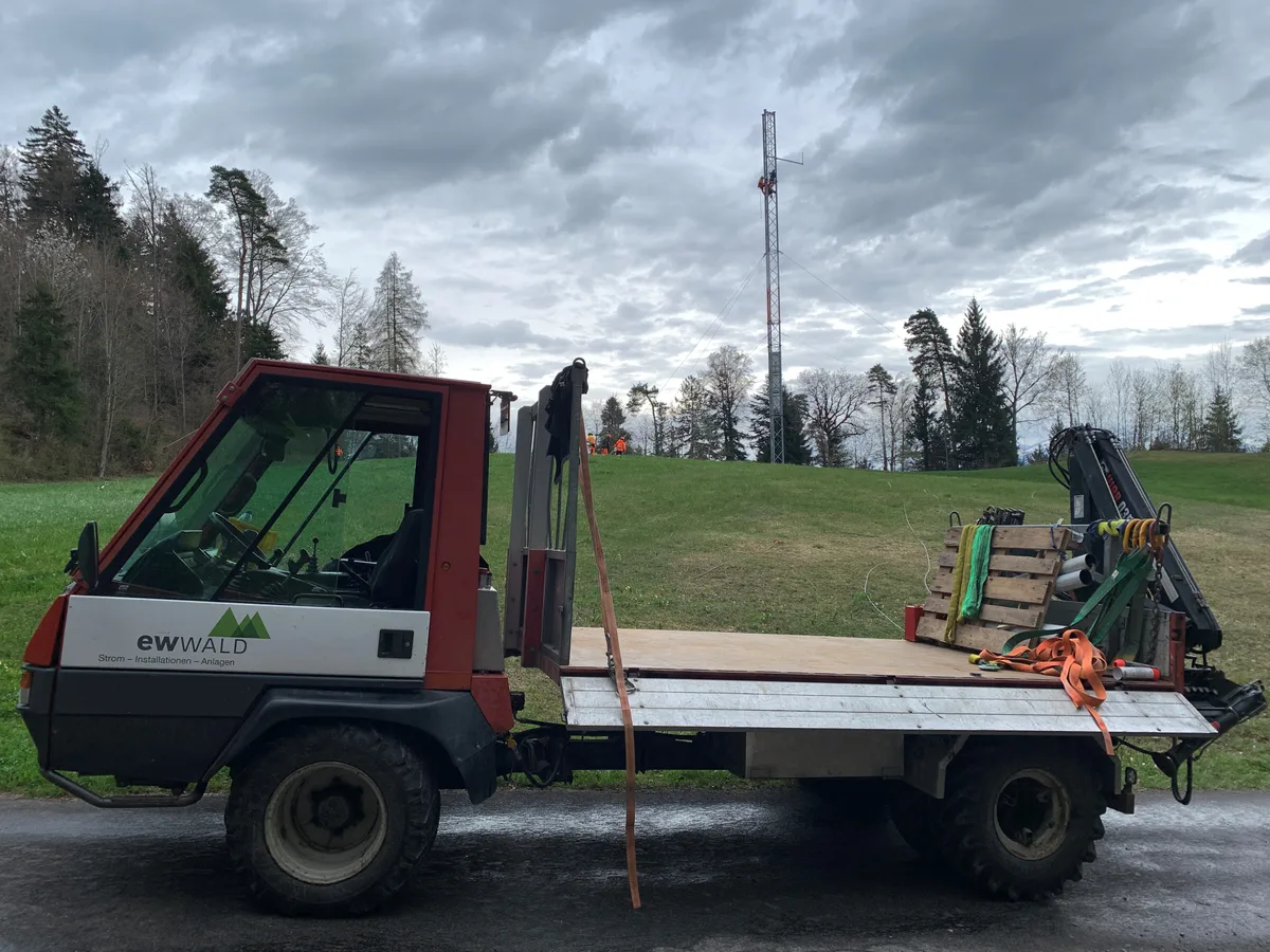 Im Vordergrund steht ein Transporter, im Hintergrund ist ein Mast zu sehen.