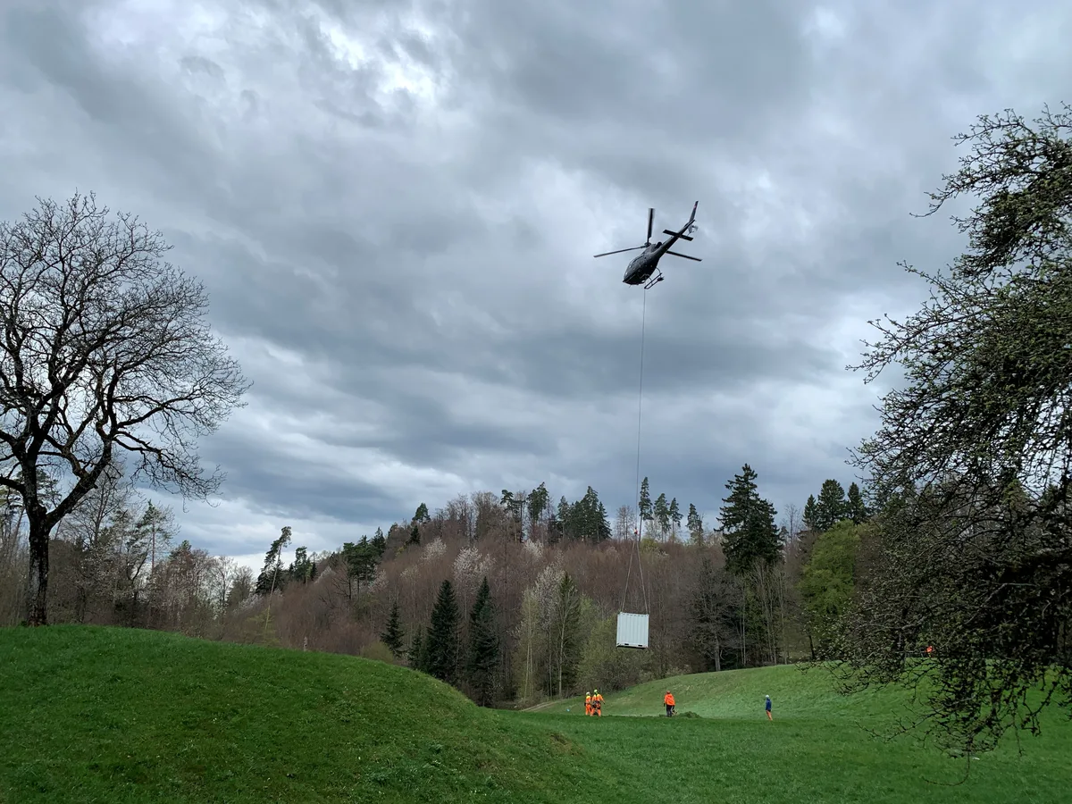 Ein Helikopter hebt einen Container an.