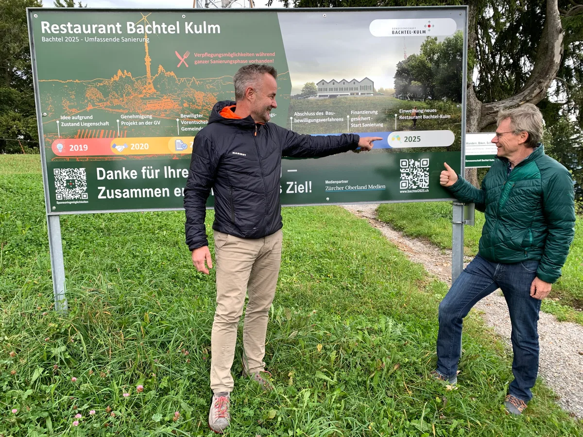 Zwei Männer stehen vor einer Werbetafel. 