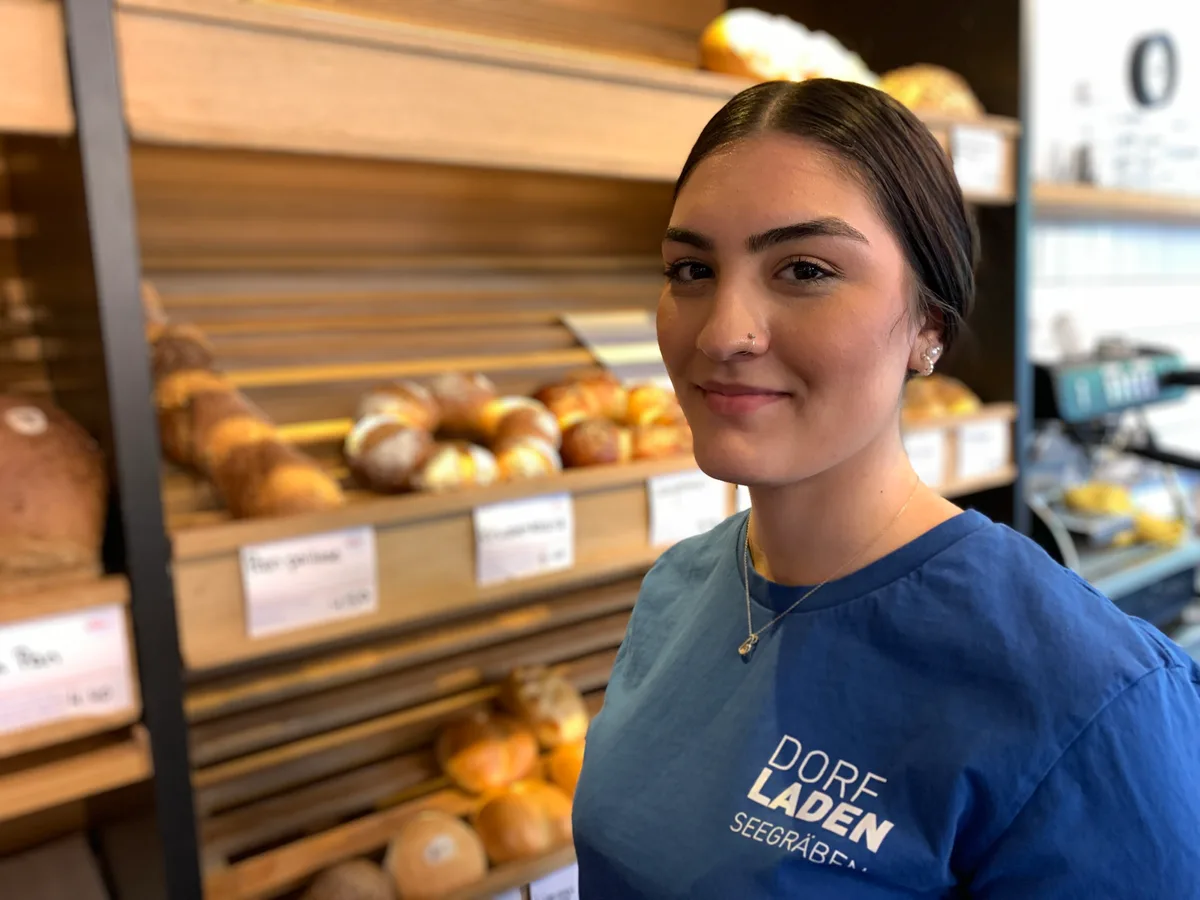 Aleyna Adiyamanlier, hier vor der Brotauslage, schliesst demnächst ihre Ausbildung zur Detailhandelsassistentin ab. Eine junge Frau steht vor einem Brotgestell.
