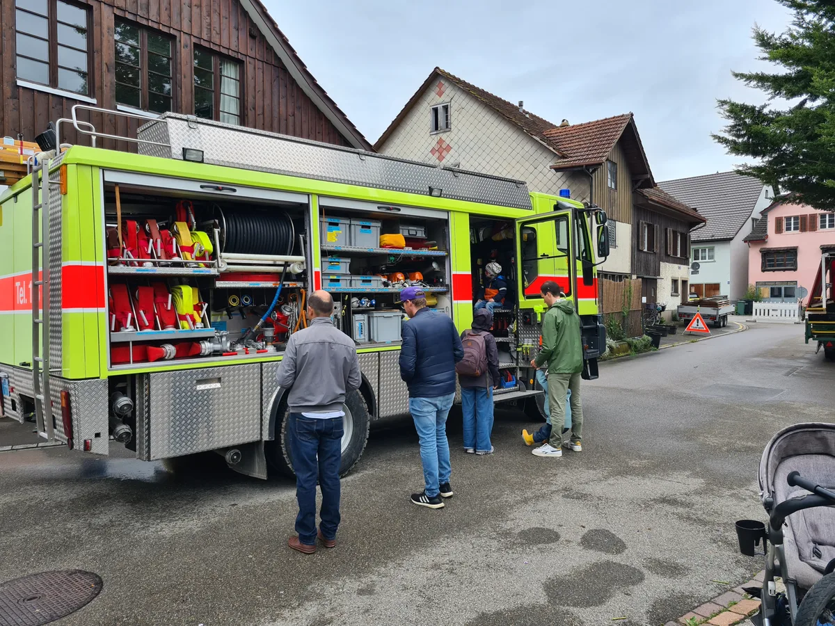 Ein Feuerwehrauto, das von Leuten angeschaut wird.