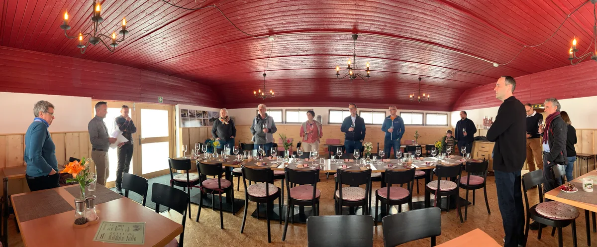 Ein Lokal mit grossem Tisch und roter Decke.