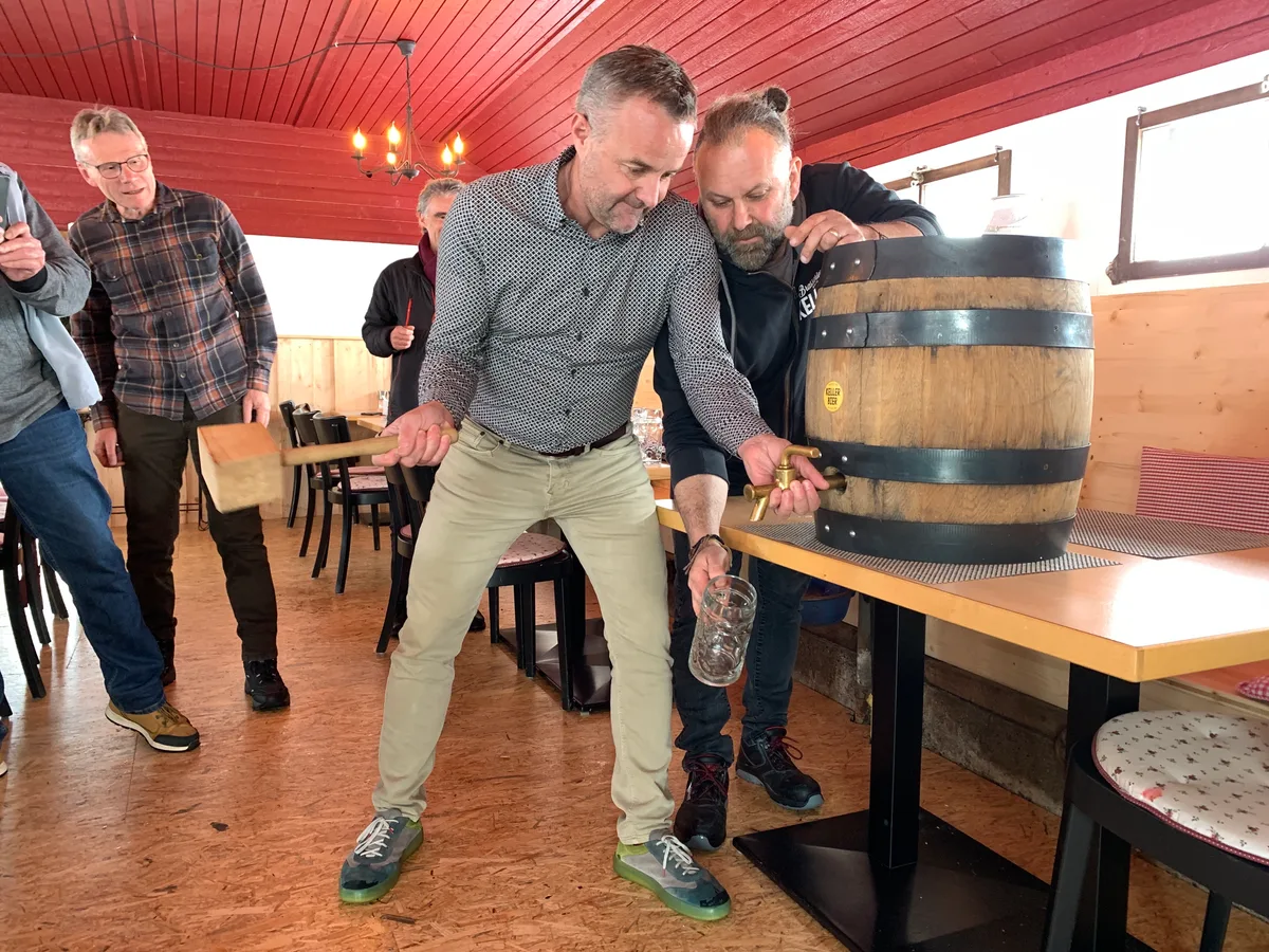 Ein Mann sticht ein Bierfass an.