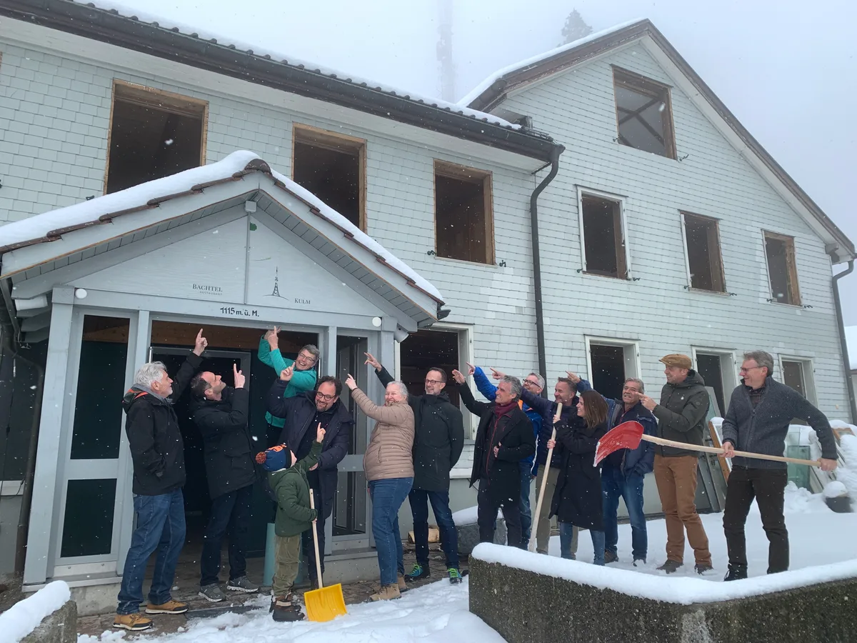 Eine Gruppe zeigt auf den Eingang des Restaurants Bachtel-Kulm, das umgebaut wird. 