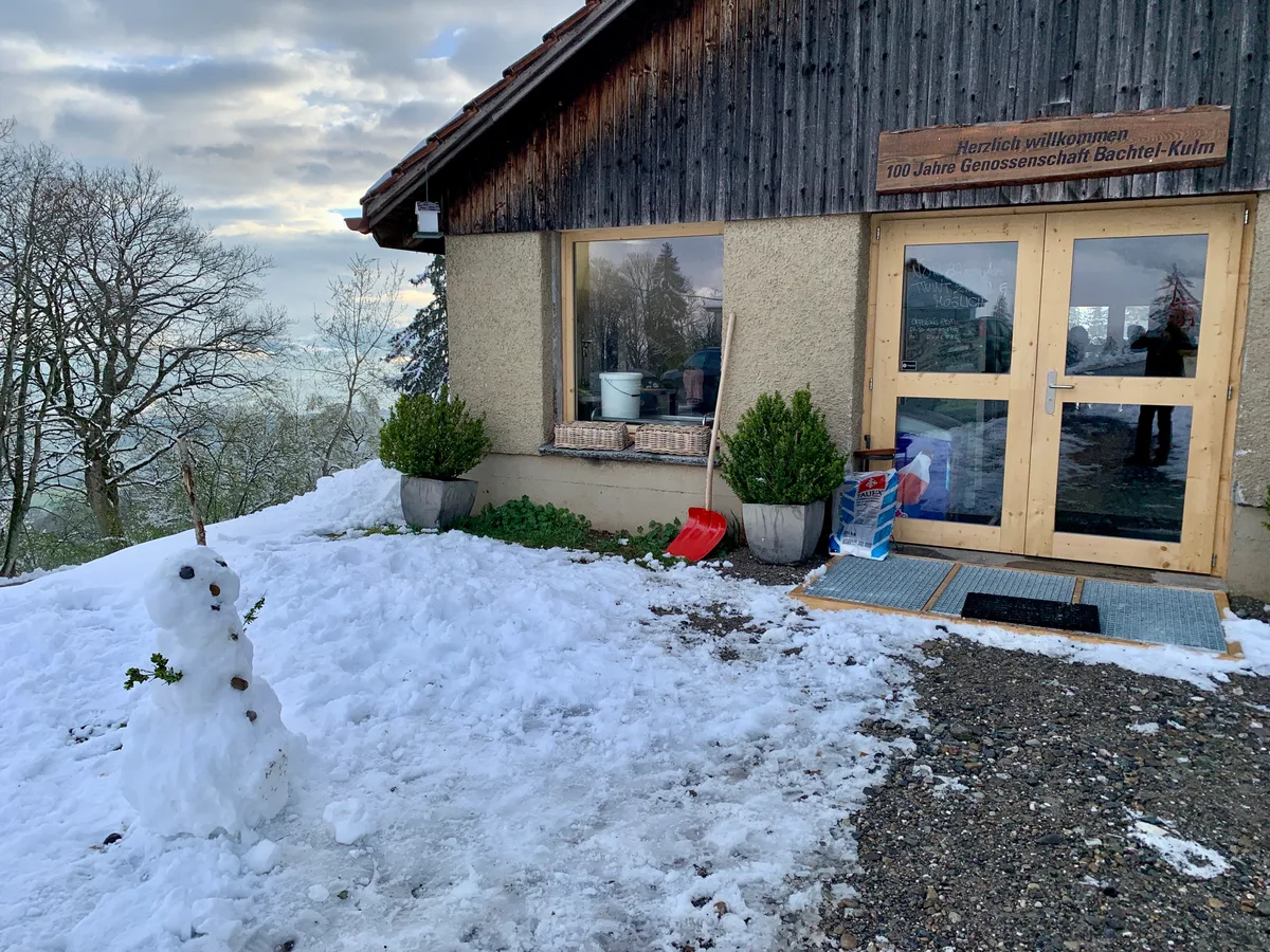 Vor dem Eingang zu einem Gebäude steht ein Schneemann.