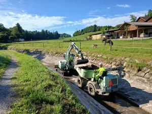26787260-5 Ein kleiner Bagger und ein Kipper reinigen den Kanal der Trümpler-Kraftwerke am 18. Juli 2025 während der Aabach-Ferien