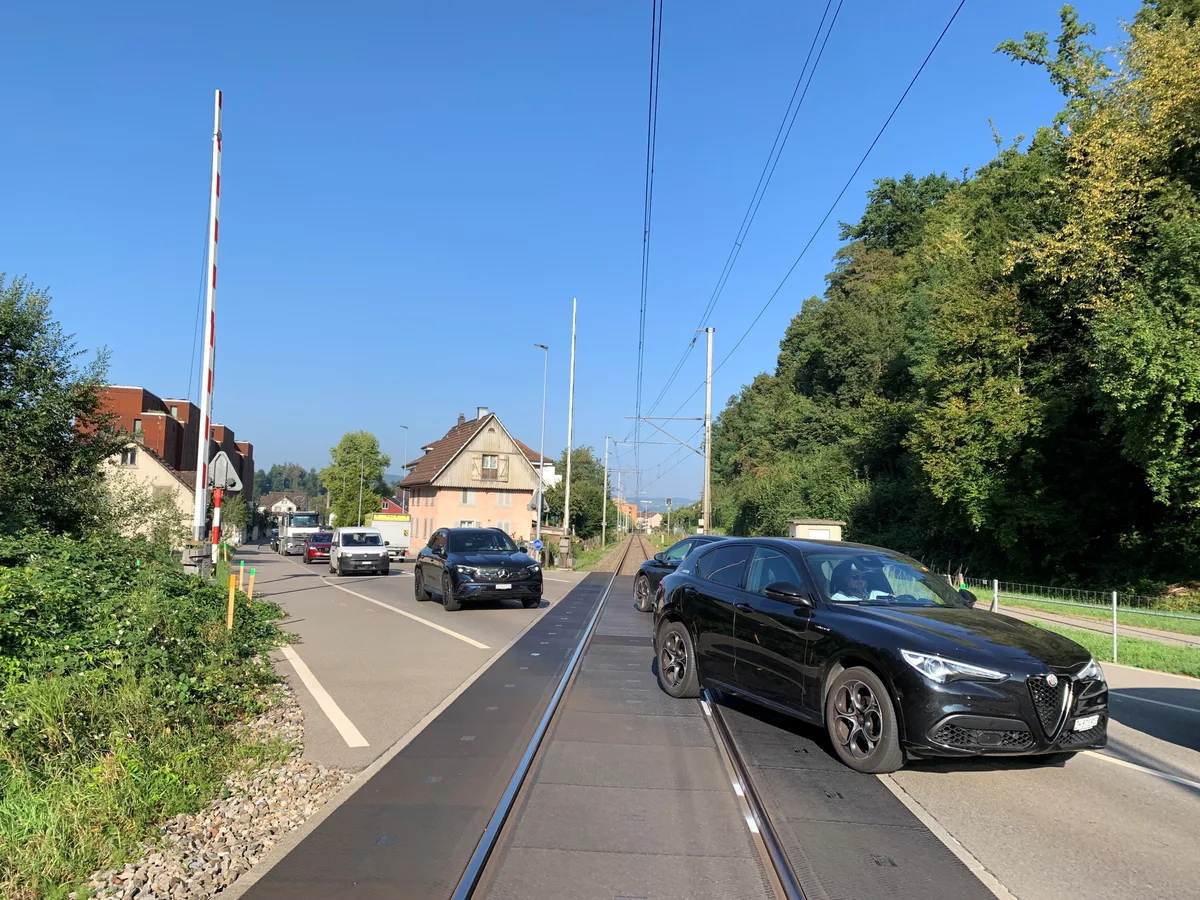 Bahnübergang in Oberuster mit Barrieren, Signal und Autos.