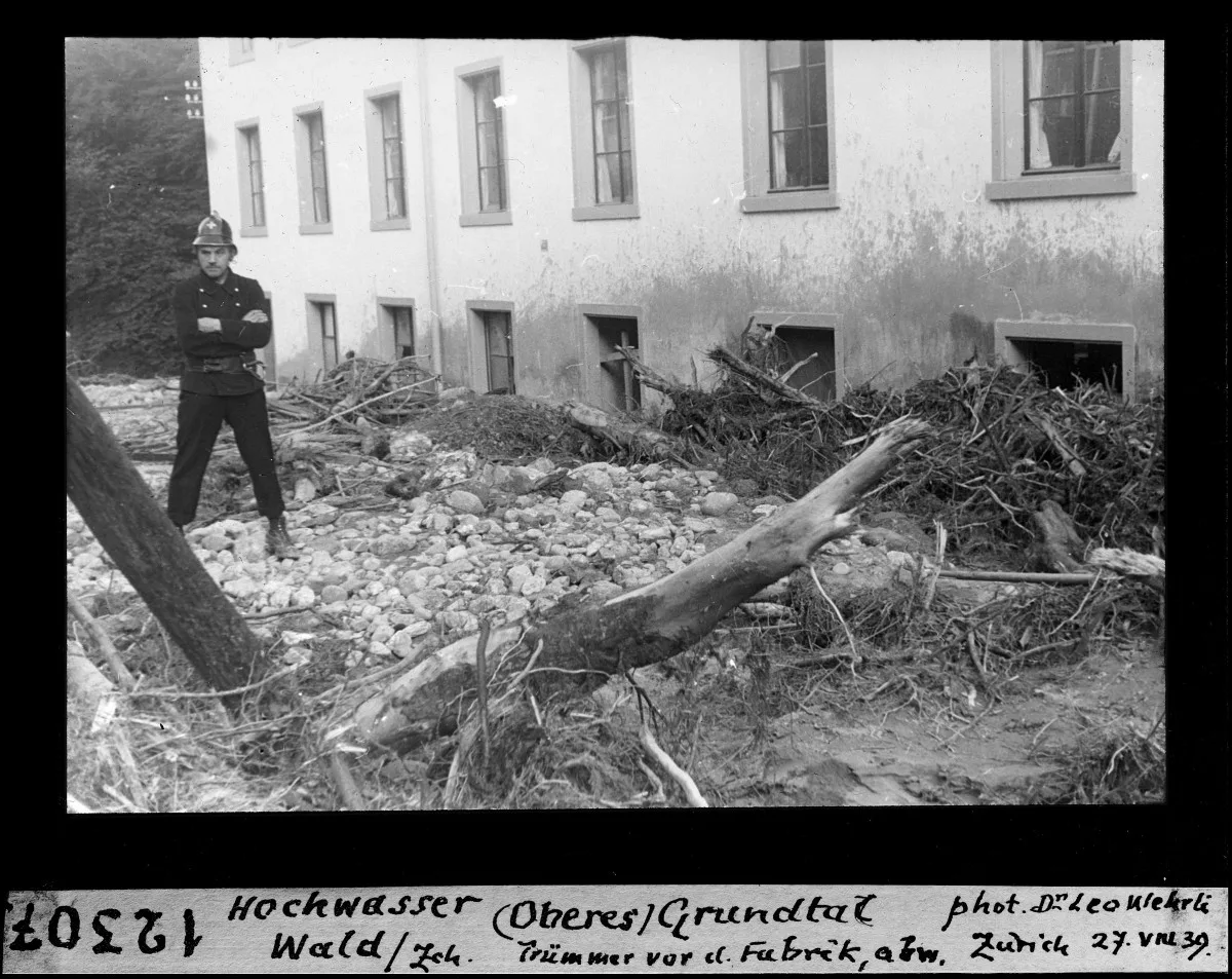 Ein Feuerwehrmann steht auf einem Haufen von angeschwemmtem Holz und Geröll.