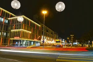 22178973-2 Sternkugeln illuminieren den Nachthimmel, während Lichterketten die Häuserzeilen schmücken.