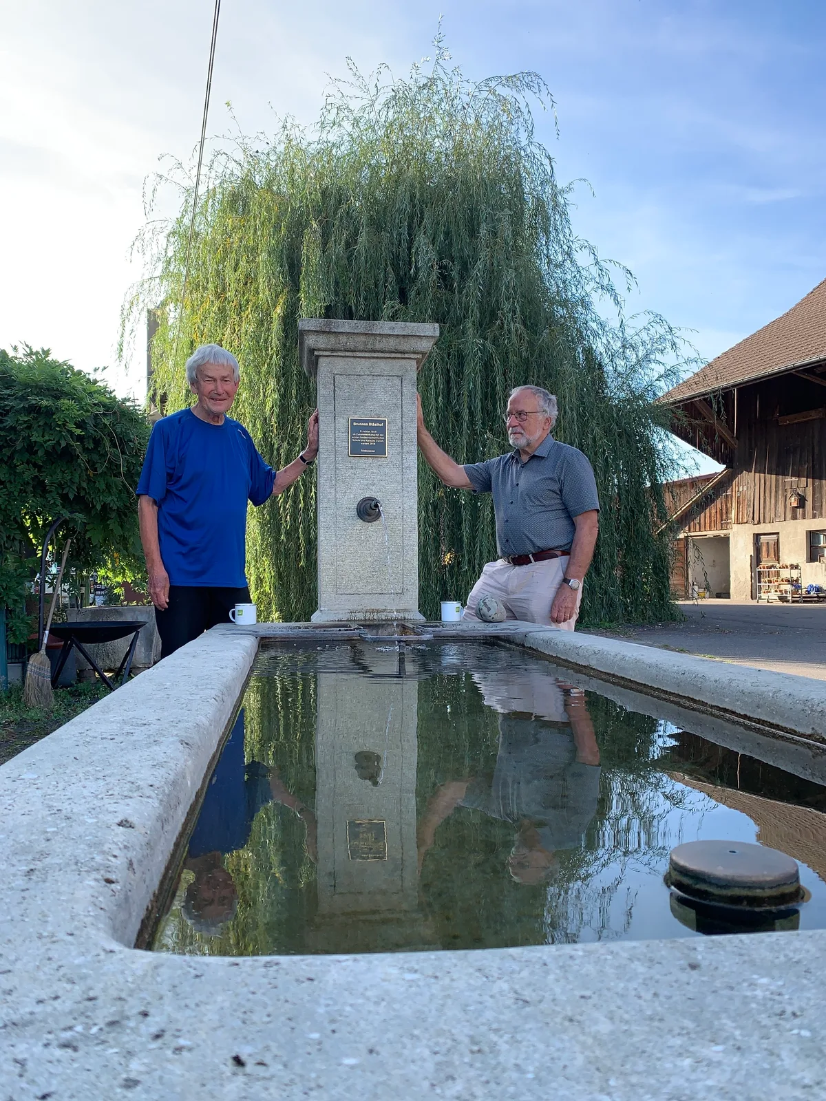 Zwei Männer stehen an einem alten Brunnen.