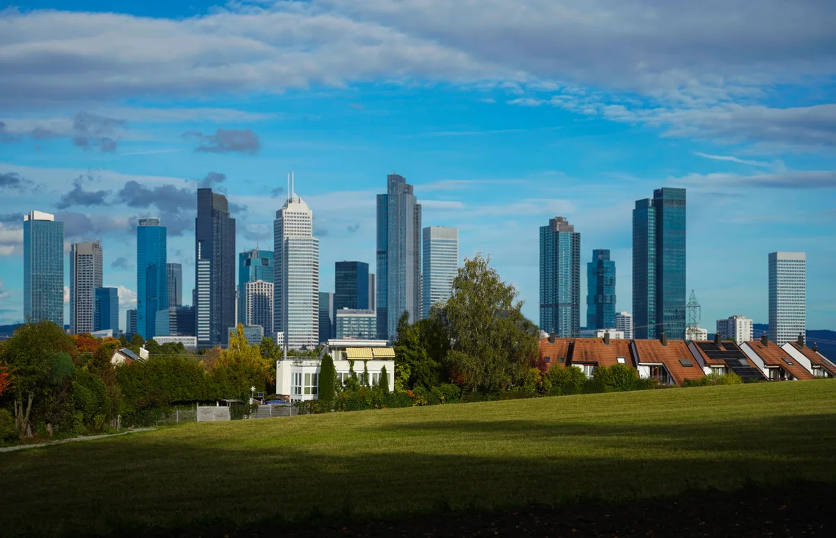 Ein Dorf und übertriebene Hochhäuser im Hintergrund.