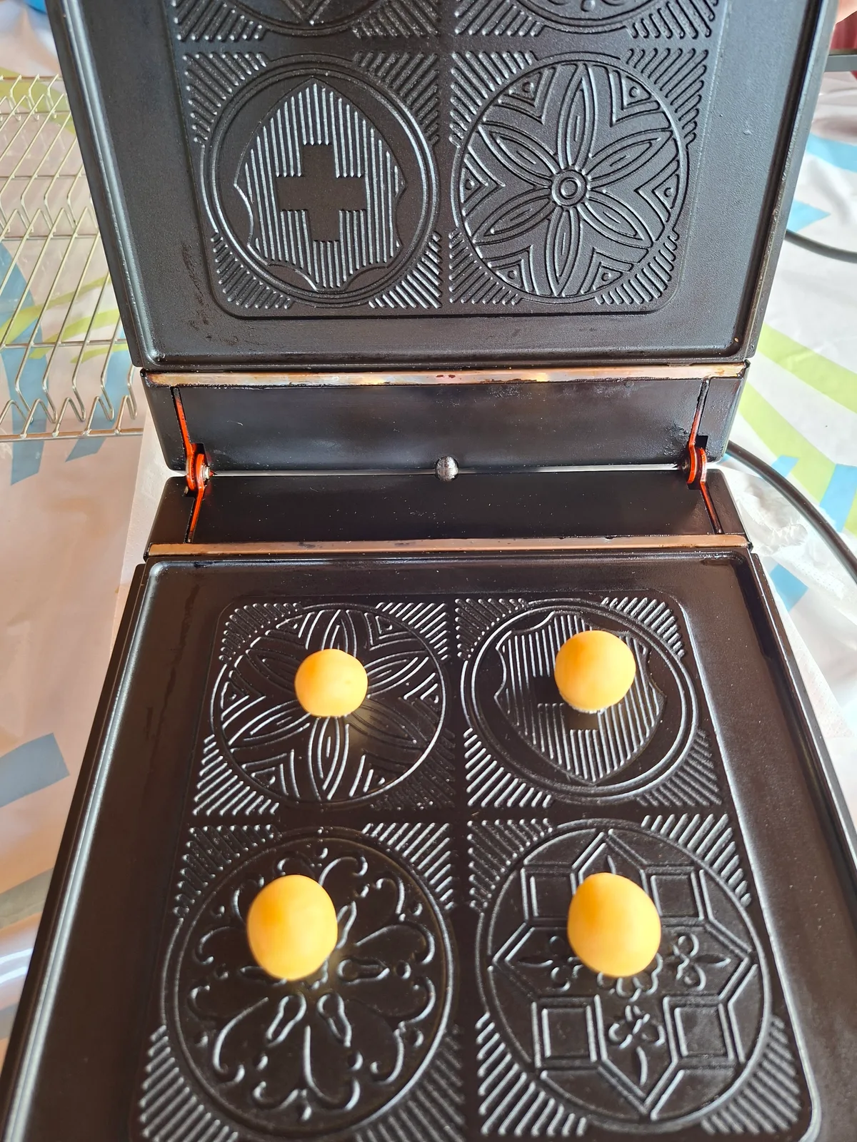 Brezelteigkugeln liegen im Brezeleisen bereit um gebacken zu werden.