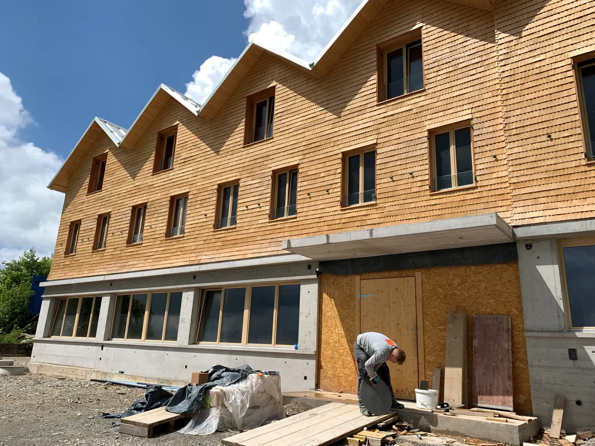 Die Schindelfassade des Restaurants Bachtel-Kulm mit einem Arbeiter im Vordergrund.