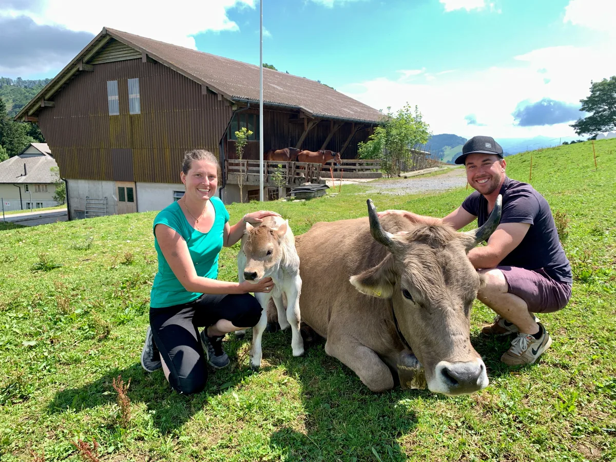 Monika und Manuel Schuler zeigen sich zusammen mit einer Kuh und einem Kalb.