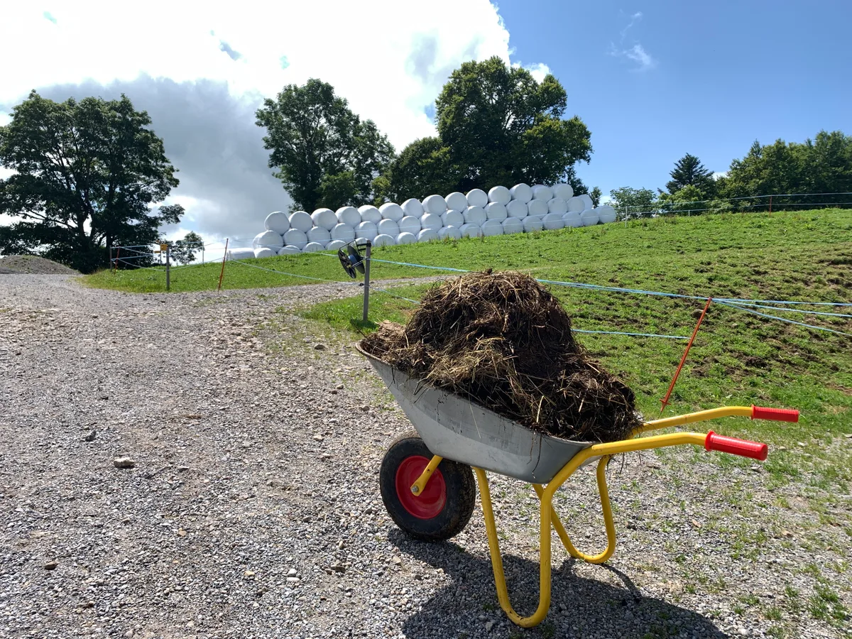 Eine Karrette steht vor einigen Siloballen.