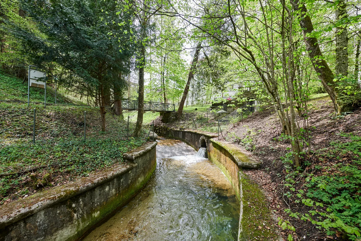 Nachdem das Wasser seine Kraft auf die Turbinen übertragen hat, fliesst es als Bächlein durch die gepflegte Parklandschaft der einstigen Fabrikherren. Wasserkraft im Museum Neuthal