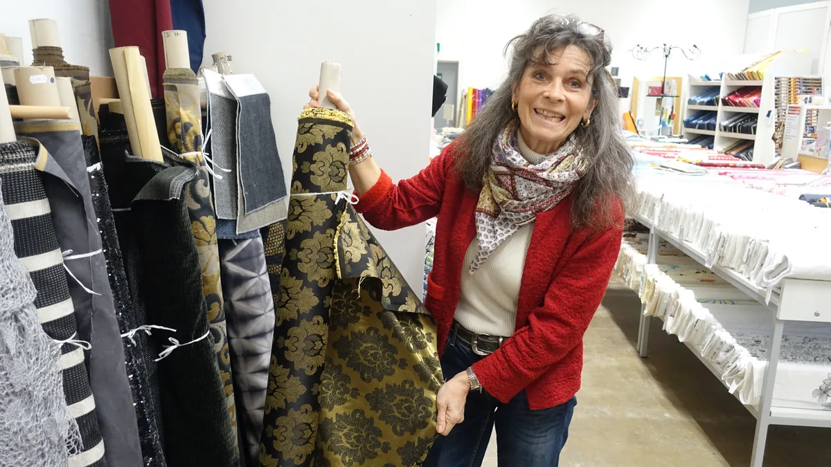 Ein goldener Stoff mit schwarzem Barockmuster.