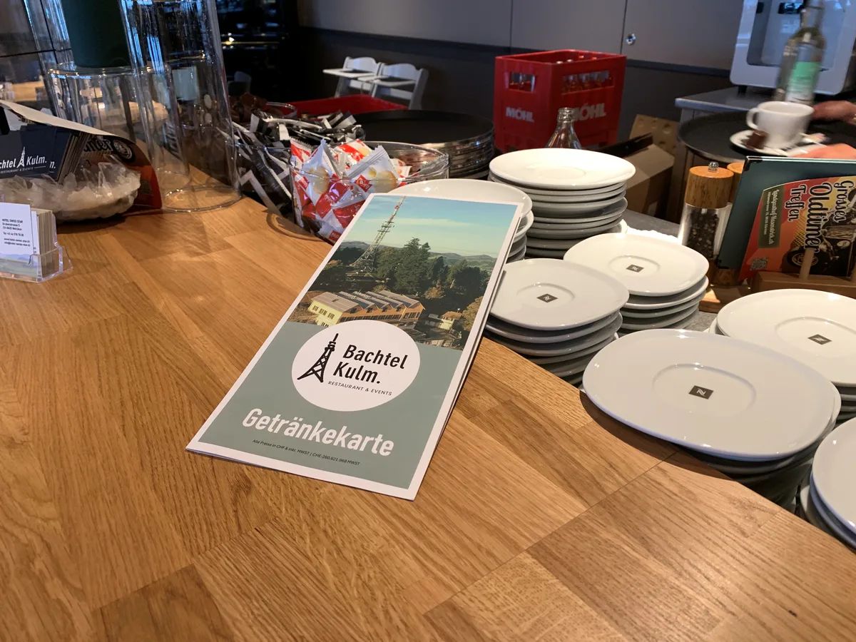 Auch auf der Getränkekarte prangt das Signet des Restaurants Bachtel-Kulm. Eine Getränkekarte liegt auf dem Tresen eines Restaurtants.