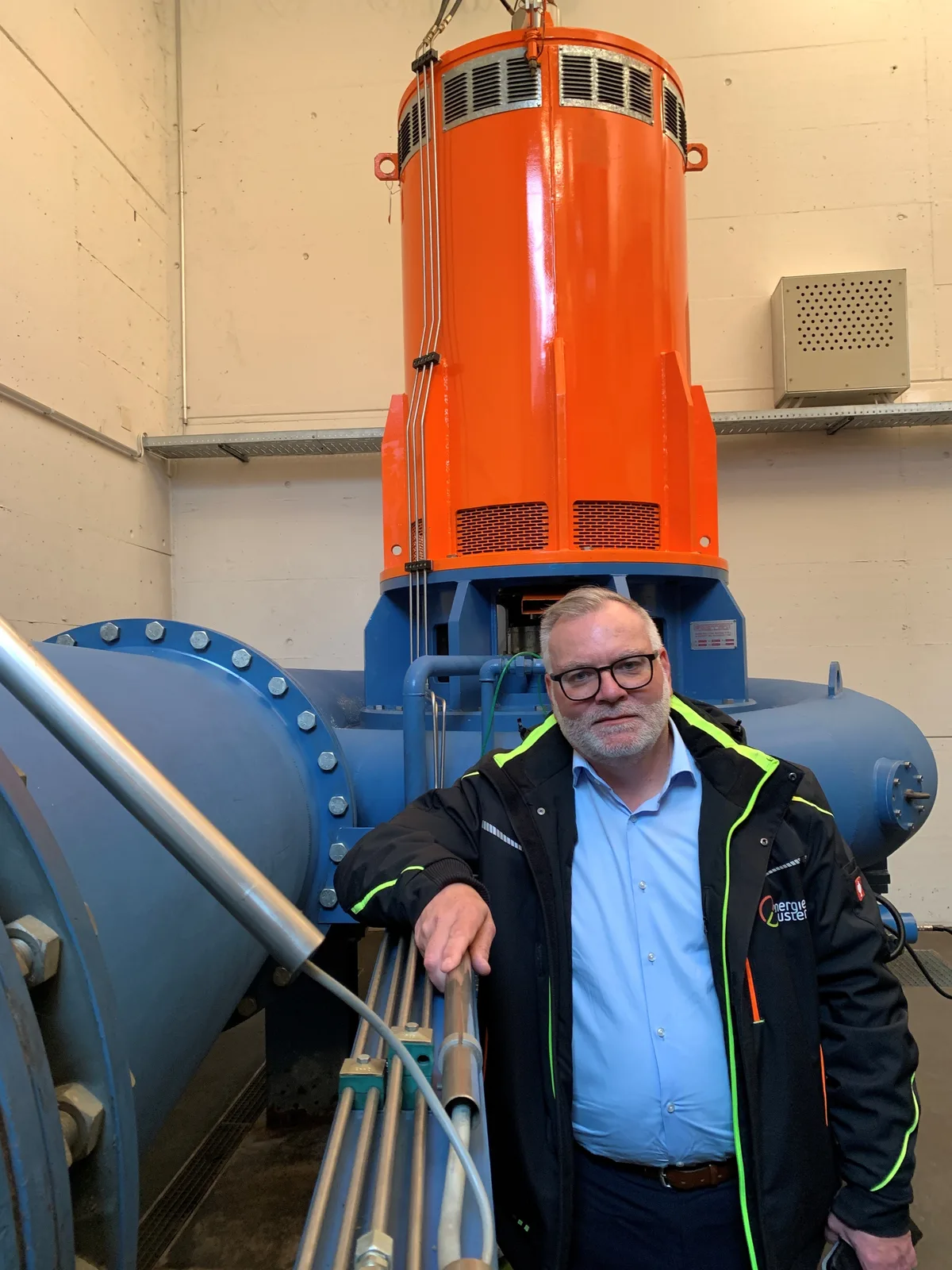 Ein Mann steht vor einer Turbine.