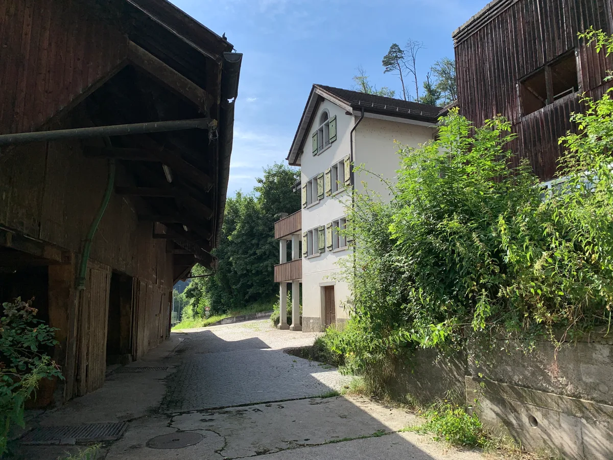 Blick auf einen Bauernhof in Aathal mit Wohnhaus, Silos und Ställen.