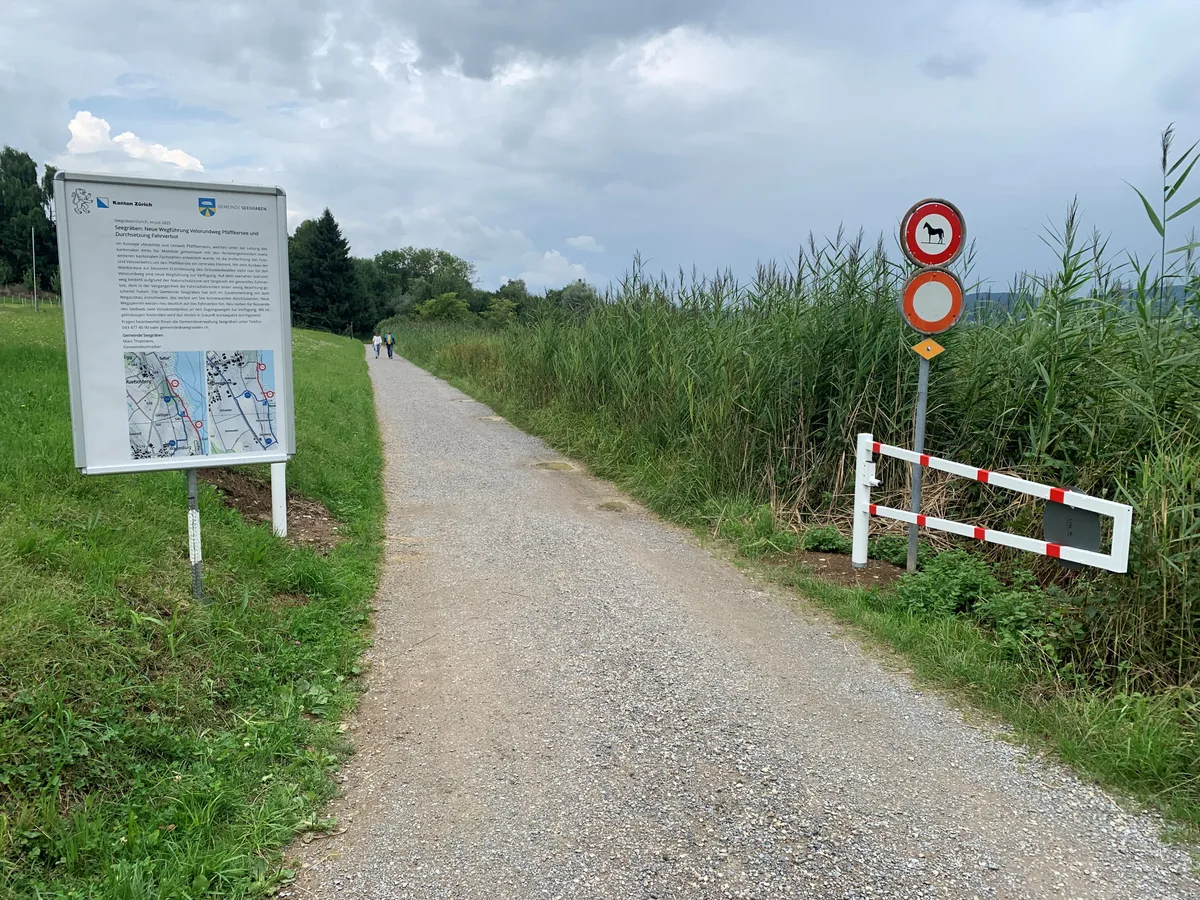 26840916-1 Entlang des Pfäffikersees gibt es auf Seegräbner Boden nun ein Velofahrverbot. Es wurden Schranken aufgestellt sowie Veloabstellplätze (der eingehagte Baumstamm). Aufnahme kurz vor Einführung am 26. Juli 2025 bei der Schlachtmad, Abzweiger Weg nach Auslikon)
