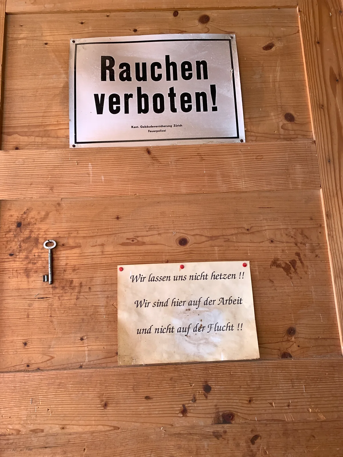 Eine Tür mit einem aufgehängten Schlüssel sowie zwei Plakaten.