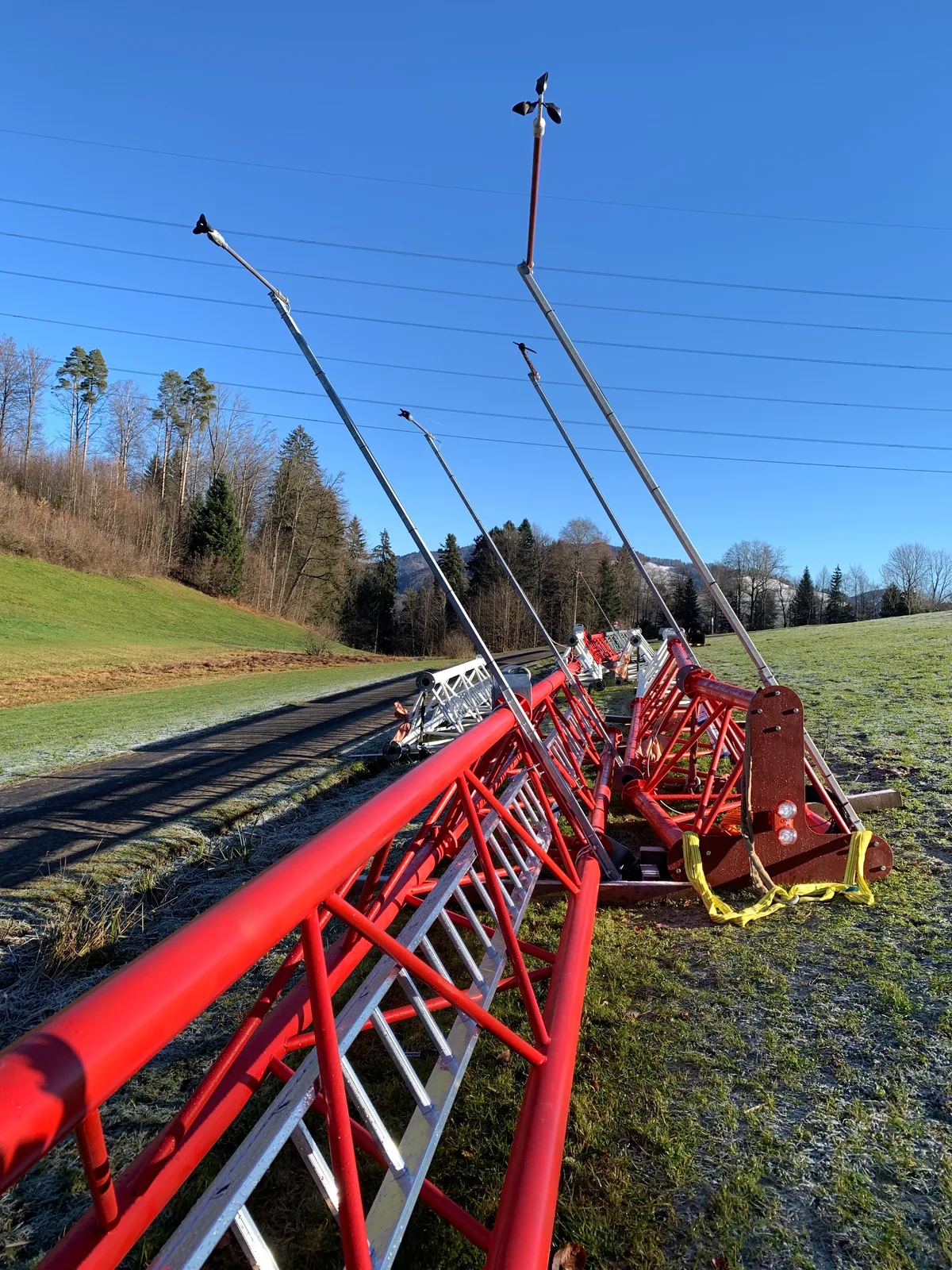Auf einer Wiese liegen mehrere Teile eines Masts.