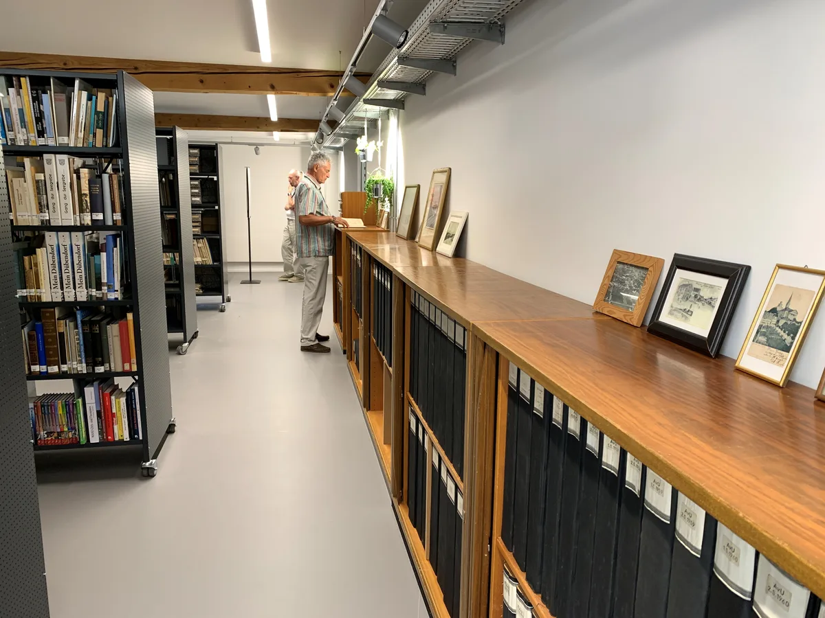 Verschiedene Regale mit kleinen und grossen Büchern sind in einem Raum aufgereiht. 