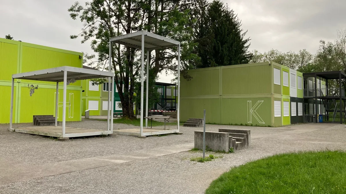Verschiedene Schulcontainer stehen in einem Park.