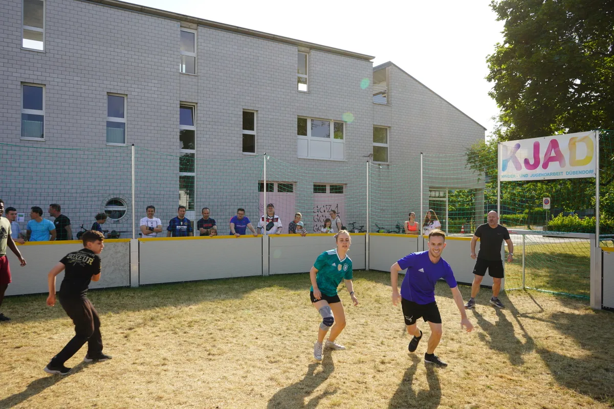 Ältere und jüngere Menschen spielen zusammen Fussball.