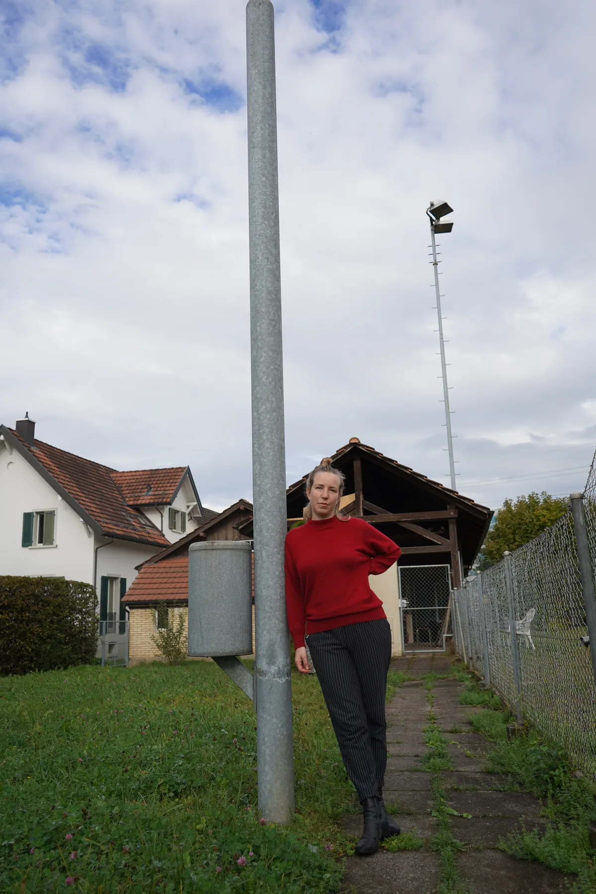 Eine Frau lehnt an eine Flutlichtstange.