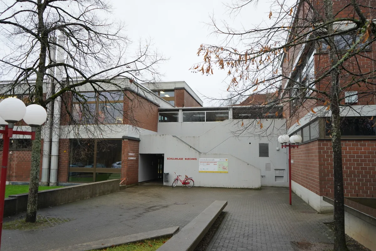 Ein Schulhaus mit einem rotem Velo davor.