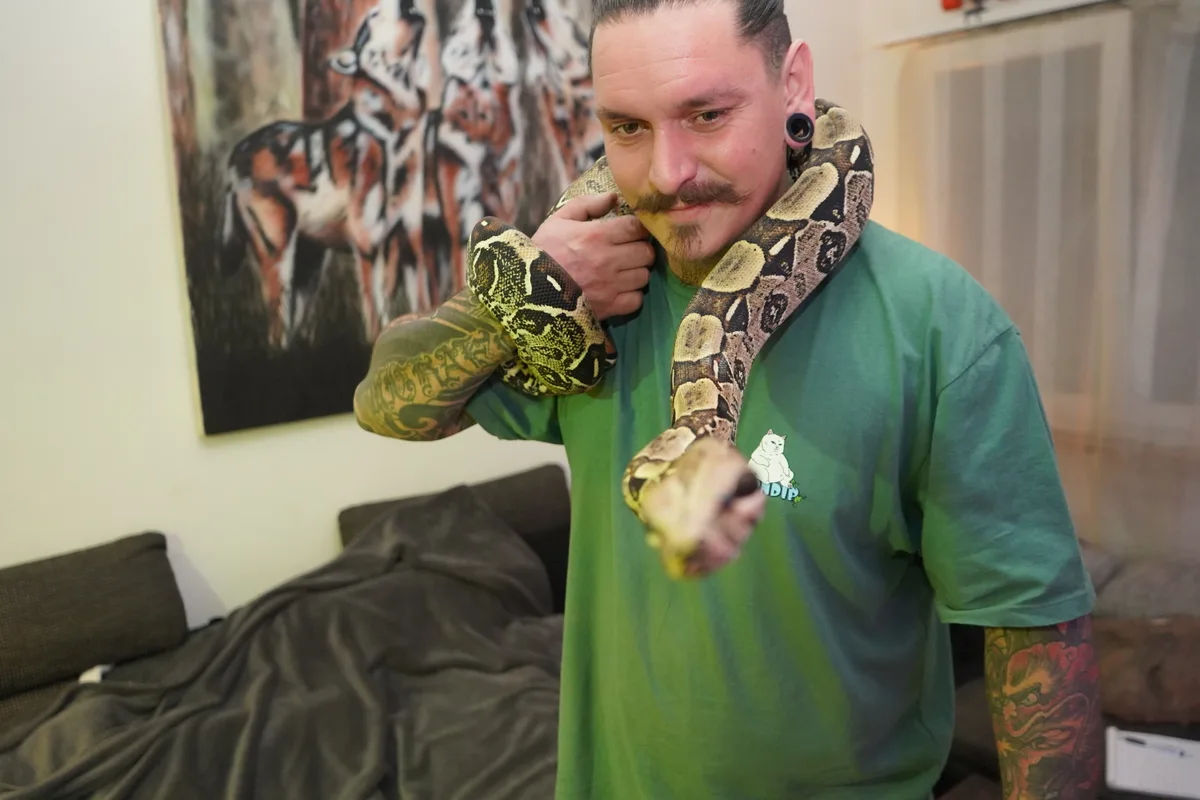 EIn Mann mit einer Schlange um den Hals. 