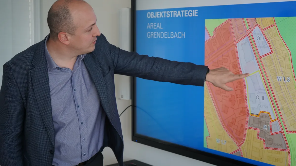 Mann mit Anzug steht vor Screen mit Karte.