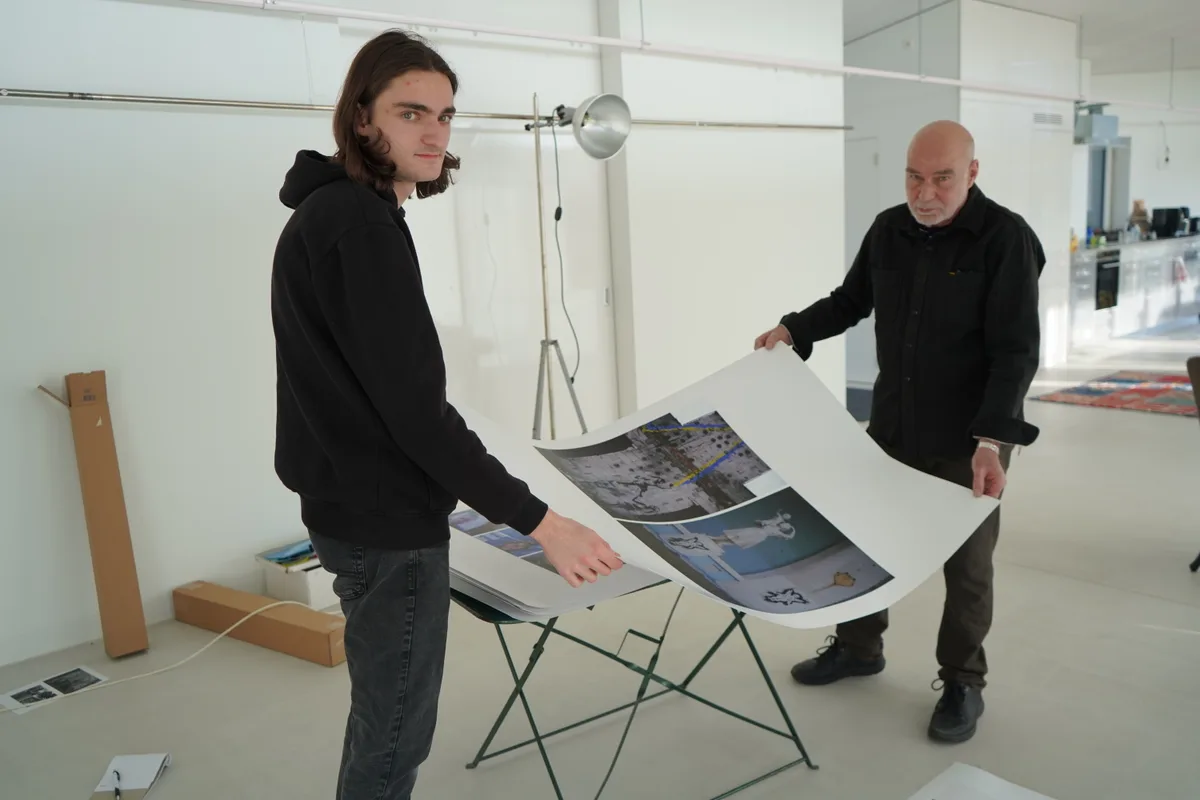 Urs und Gian Walder halten Plakate der Ausstellung hoch.