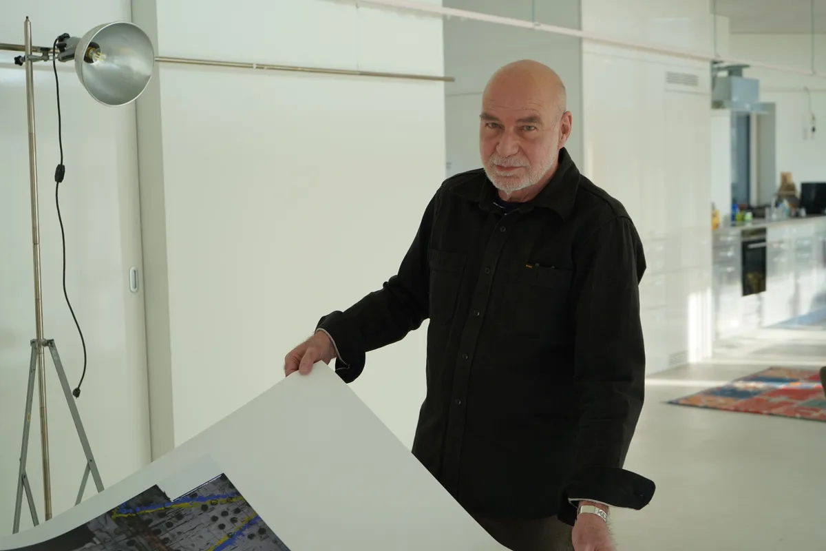 Urs Walder hält ein Plakat der Ausstellung hoch.