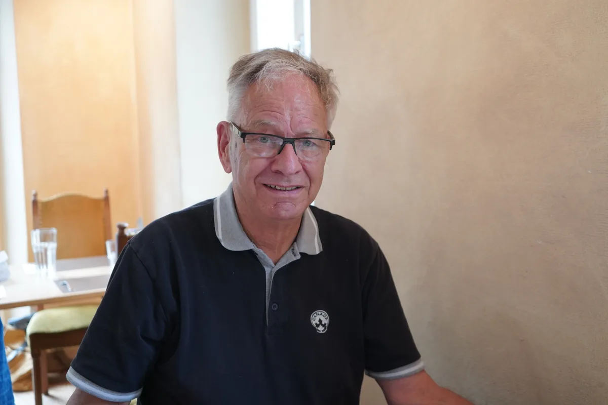 Ein älterer Mann mit Brille sitzt in einem Restaurant.