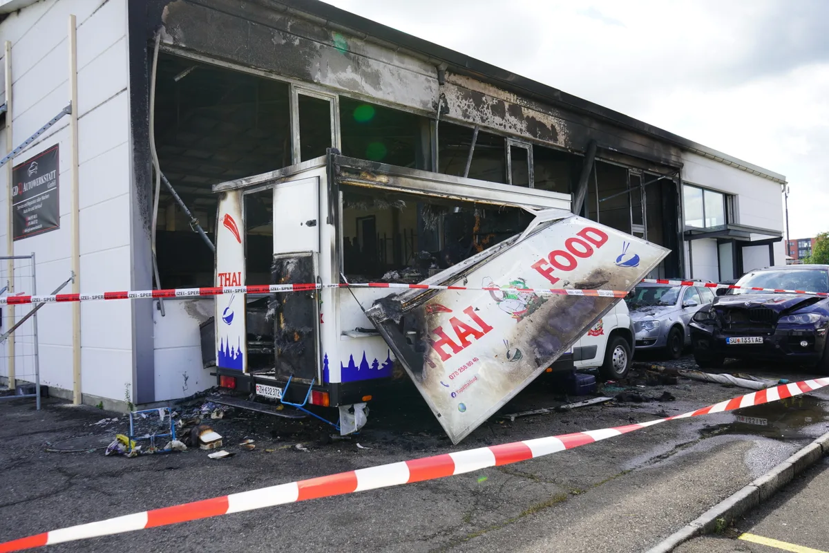 Ausgebrannte Autogarage. ein verbrannter Food Truck und verbrannte Autos in einer Autowerkstatt.