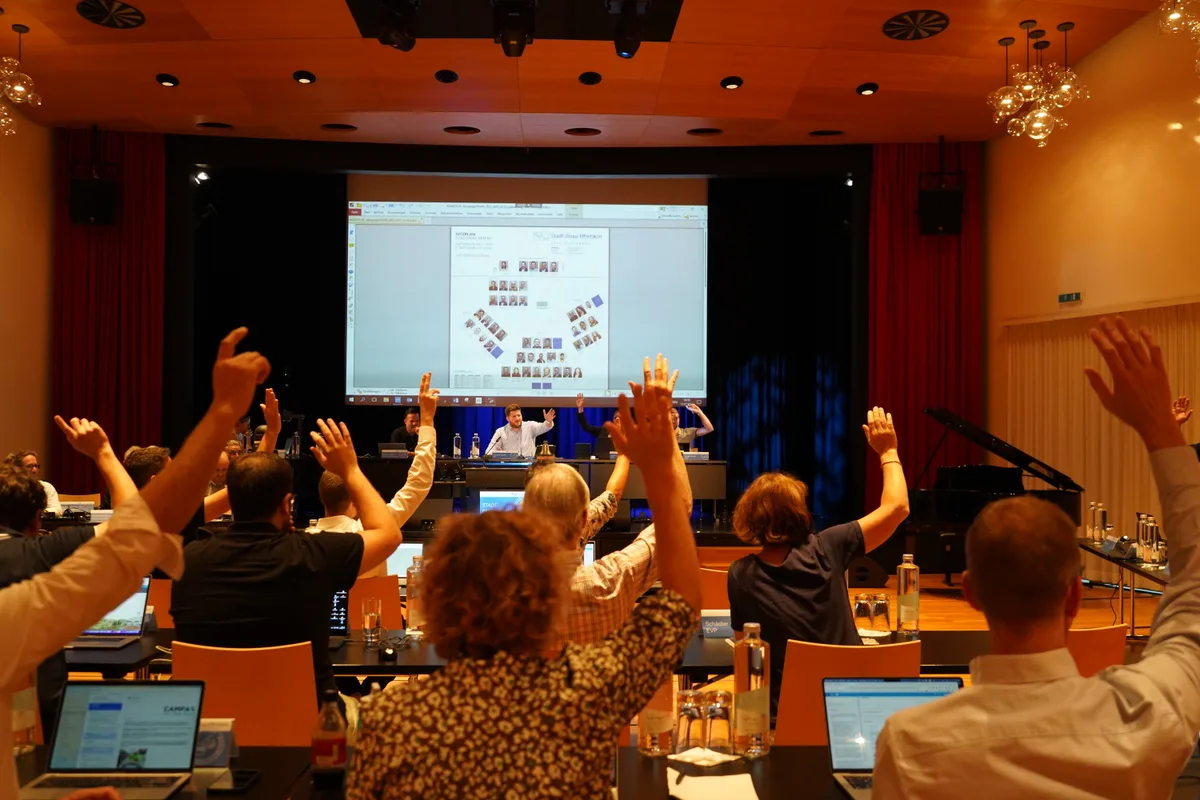 Parlamentarier heben ihre Hand in die Luft.