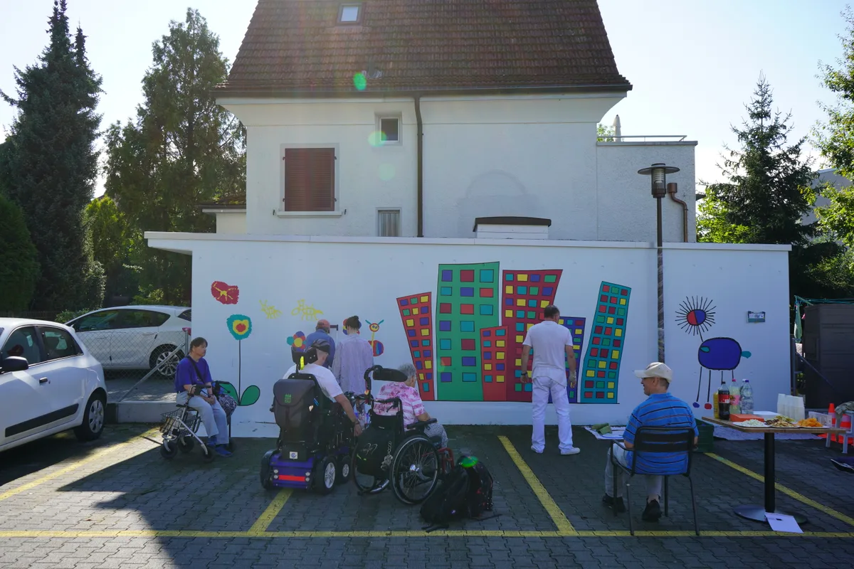 Menschen vor einer bemalten Garagenwand.