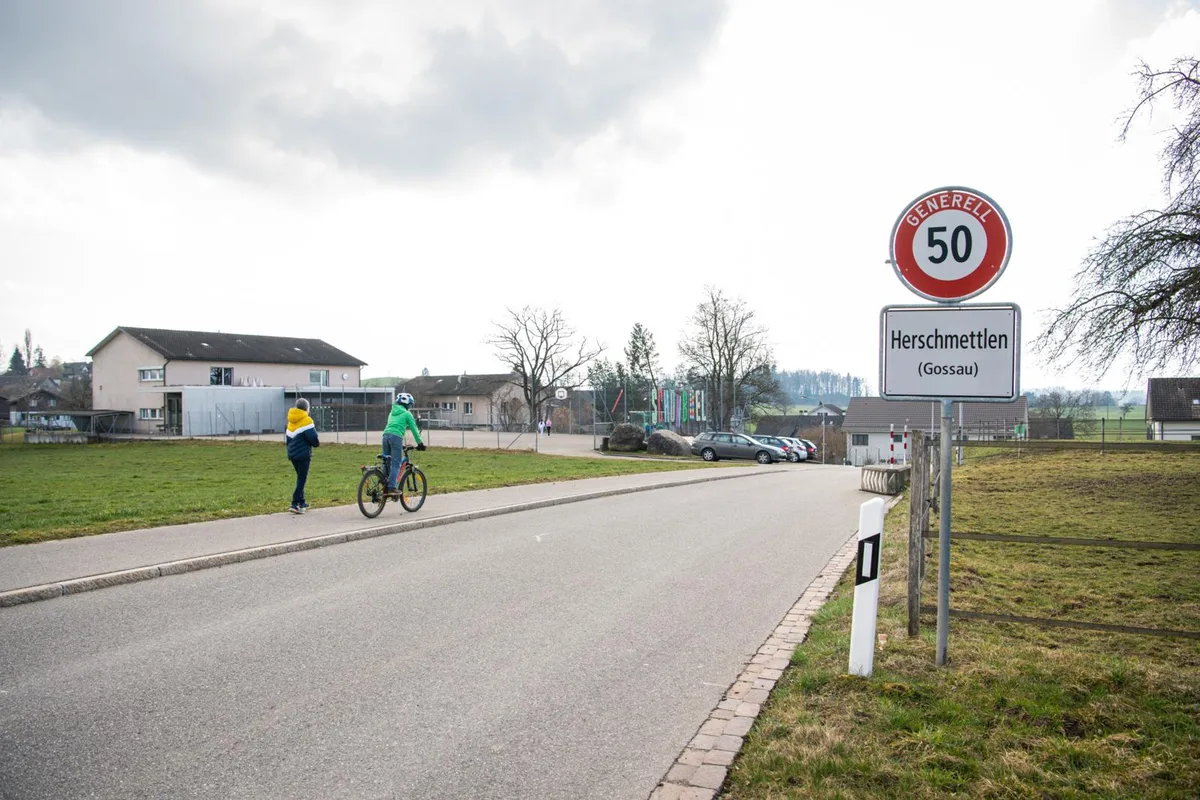 Zwei Kinder auf einer Strasse vor einem Schulhaus.