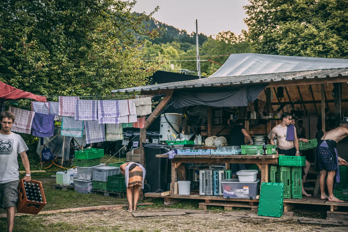 An der Abwaschstation wird das Geschirr auf Hochtouren abgewaschen, damit es immer genug hat. Helfer waschen Geschirr.