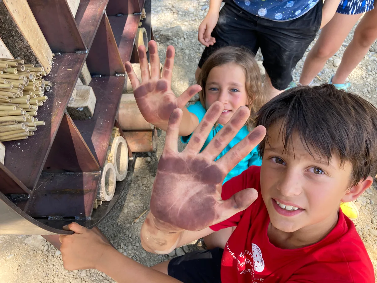 Kinder aus dem Maurmer Primarschulhaus Pünt zeigen ihre von der Stahlkonstruktion gefärbten Hände..