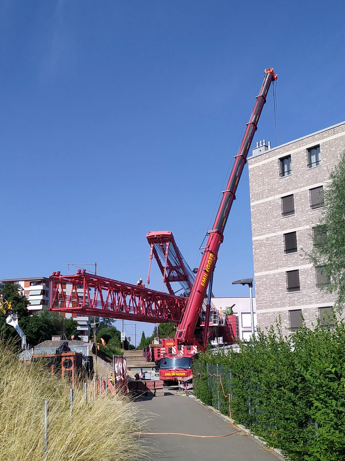 Er besteht aus mehreren Modulen, die vor Ort zusammengebaut werden. Man sieht einen Kran.