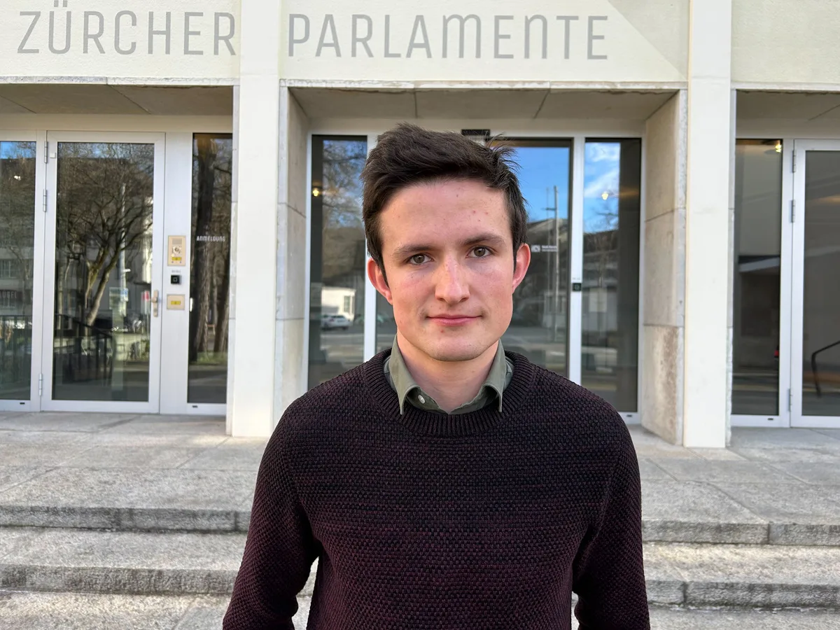 Kantonsrat Benjamin Walder (Grüne) aus Wetzikon ist neues Mitglied in der Kommission für Energie, Verkehr und Umwelt. (Archiv) Ein junger Herr steht vor einem Gebäude.