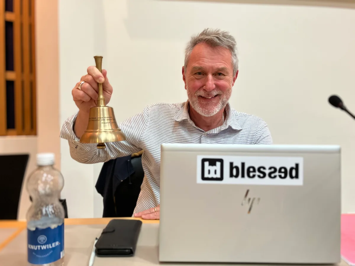 Ein Mann an einem Laptop bimmelt mit der Glocke.