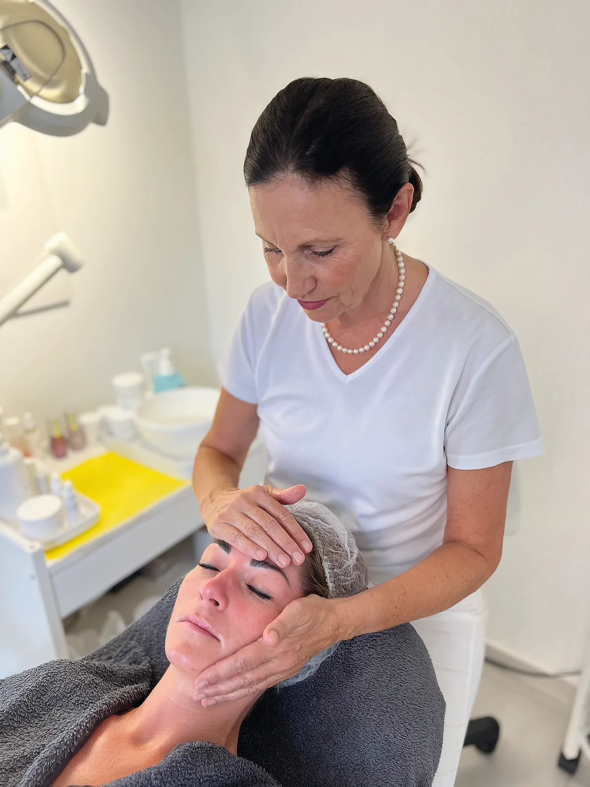 Frau macht eine Gesichtsmassage bei einer zweiten Frau