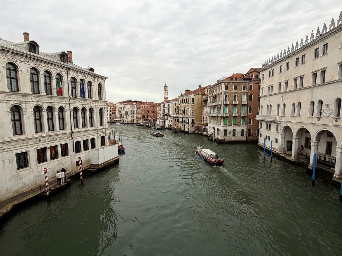 Der Blick von der Rialtobrücke auf den Canale Grande. Blick von Rialtobrücke Venedig: Zwei Wassertaxis fahren auf dem Canale Grande, der Himmel ist bedeckt.