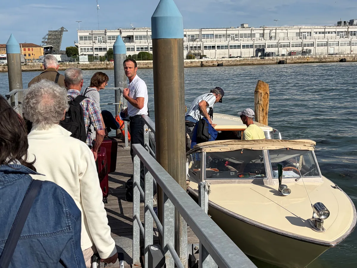 Einstieg ins Wassertaxi zum Markusplatz. Menschen mit Koffern steigen in ein Boot.